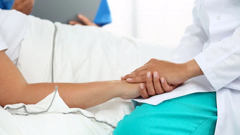 A doctor holding a patients hand