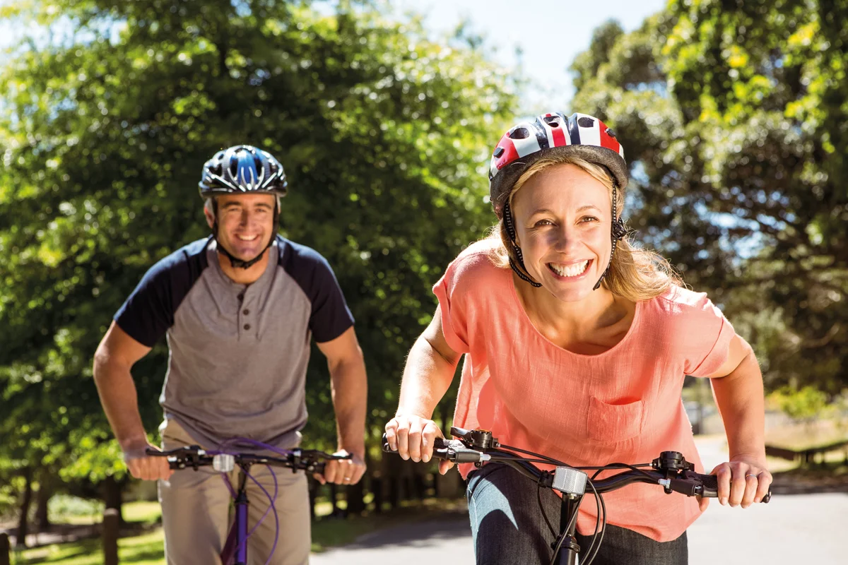 Two people on bicycles in a park on a sunny day