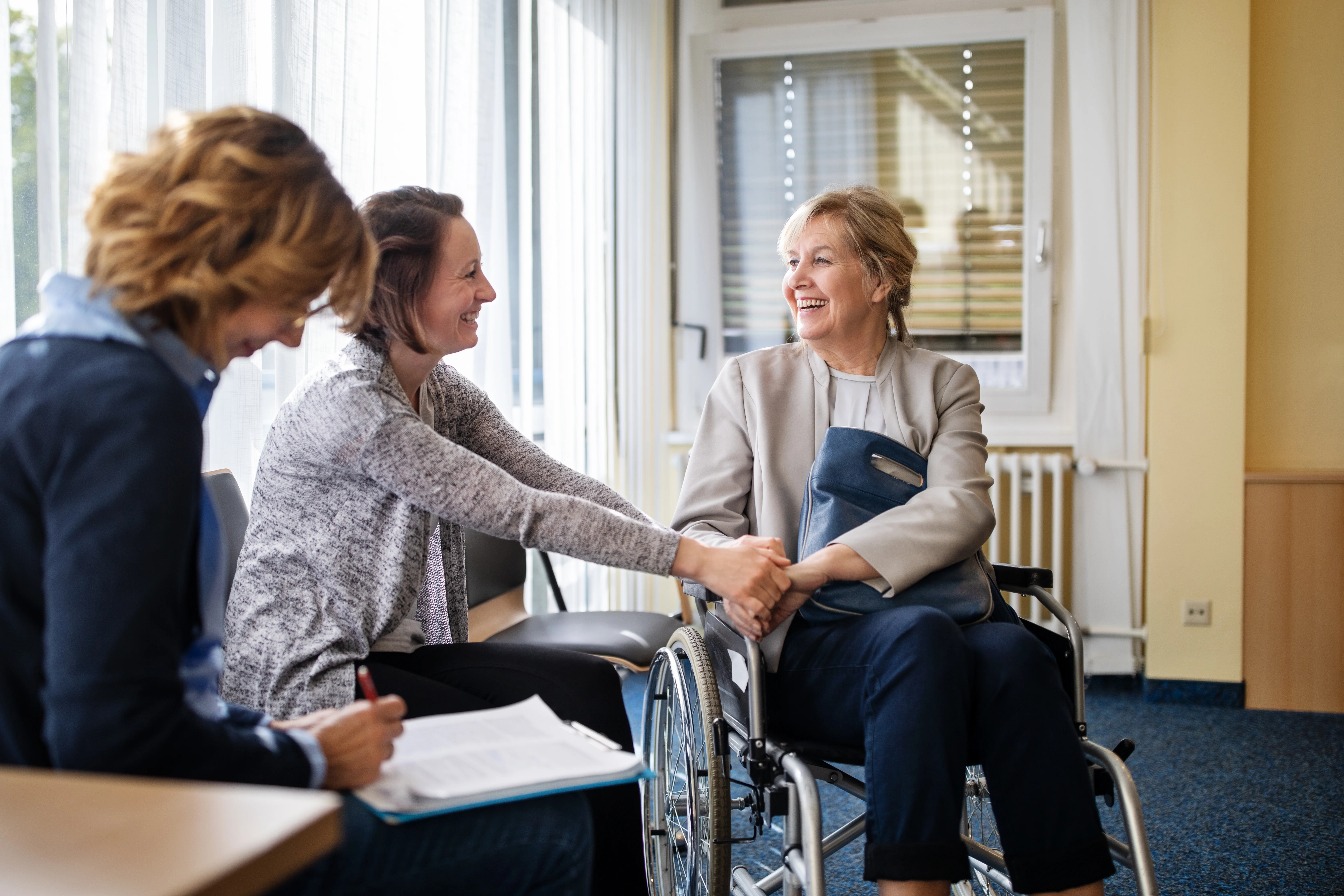 A smiling woman in a wheelchair with her doctor