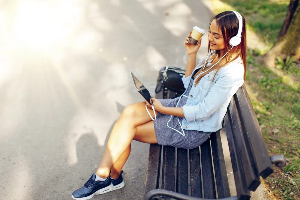 a woman sitting on a bench with a laptop and a cell phone