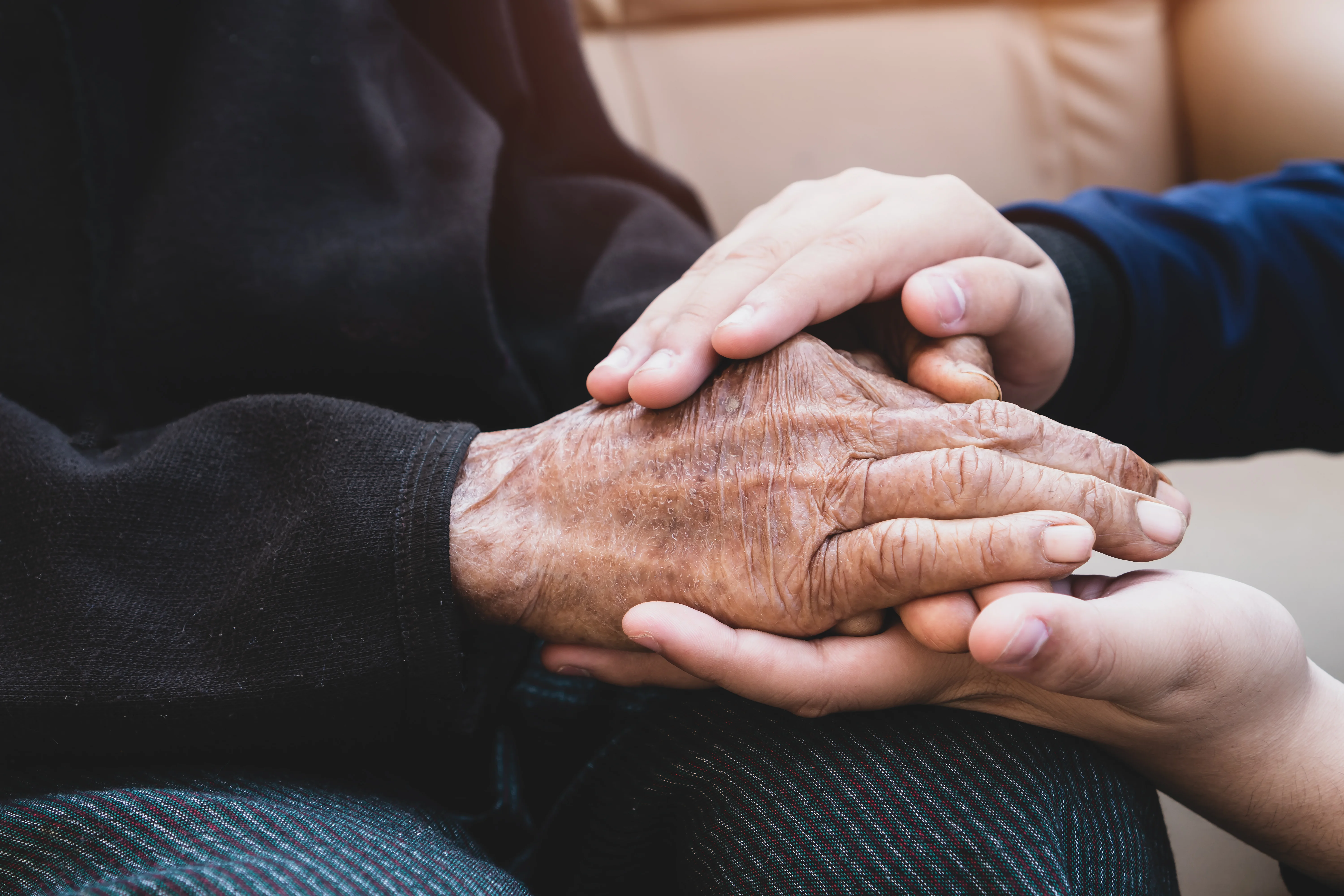 A close up of elderly hands being held by a younger pair