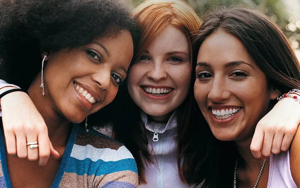 A close up of three friends hugging