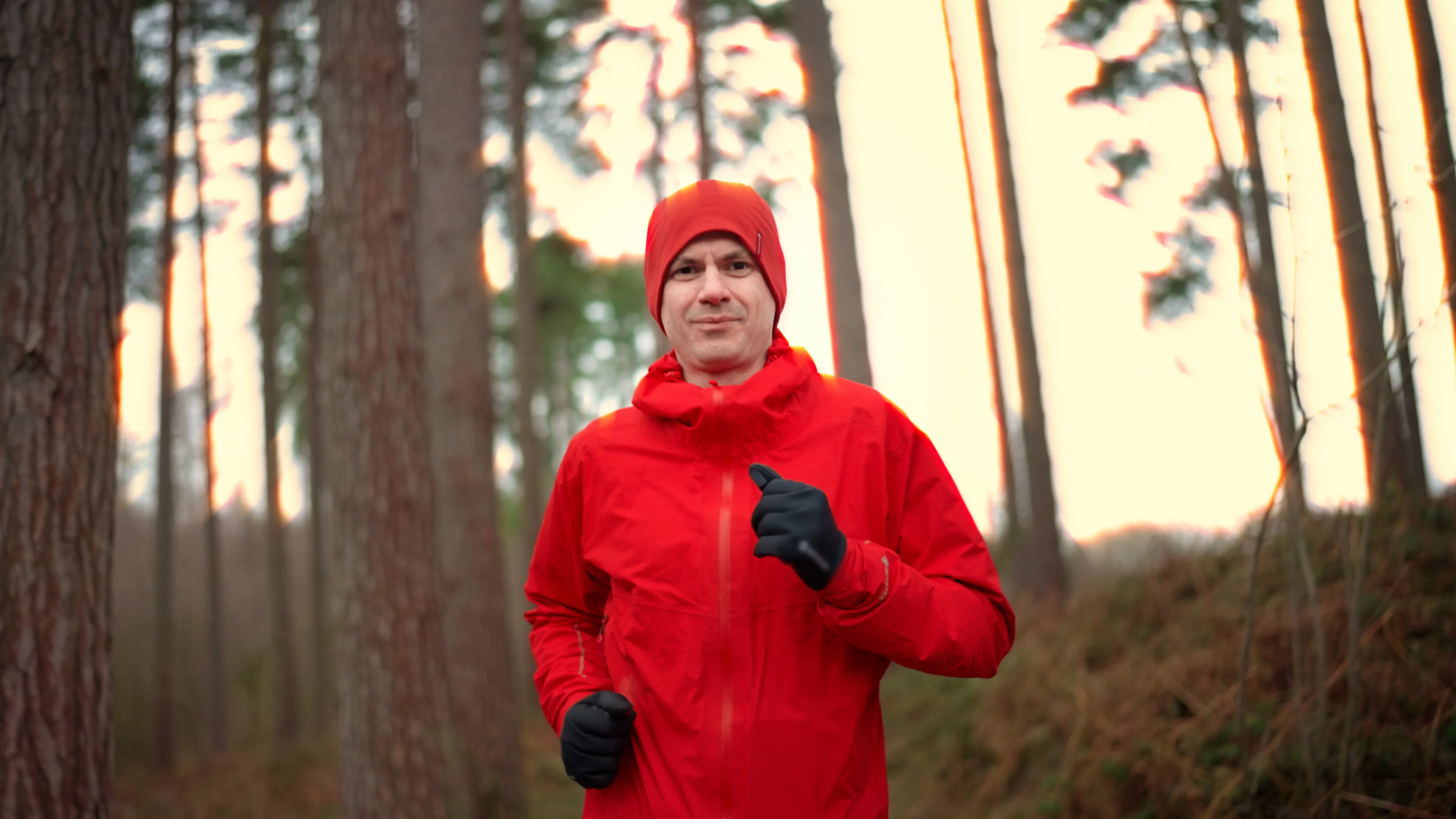 a man wearing a red coat and gloves in the woods